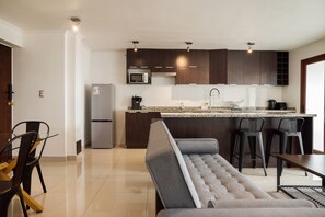 A modern kitchen with dark wood cabinets, a built-in microwave, and a stainless steel refrigerator. - Vitacura Apartments by Andes STR (Las Condes)