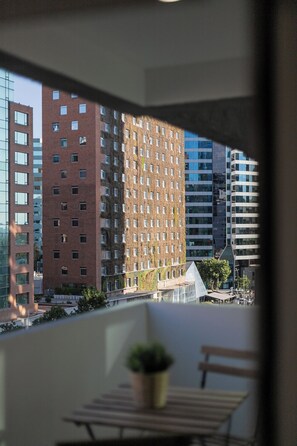 A balcony with a view of a modern building complex, including a red brick building with a unique facade and a glass structure.