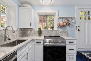 A kitchen with white cabinets, a stainless steel stove, and a sink. - The Secret Garden at Benefit~

Tranquil, starlit views in PVD with Parking! (Providence)
