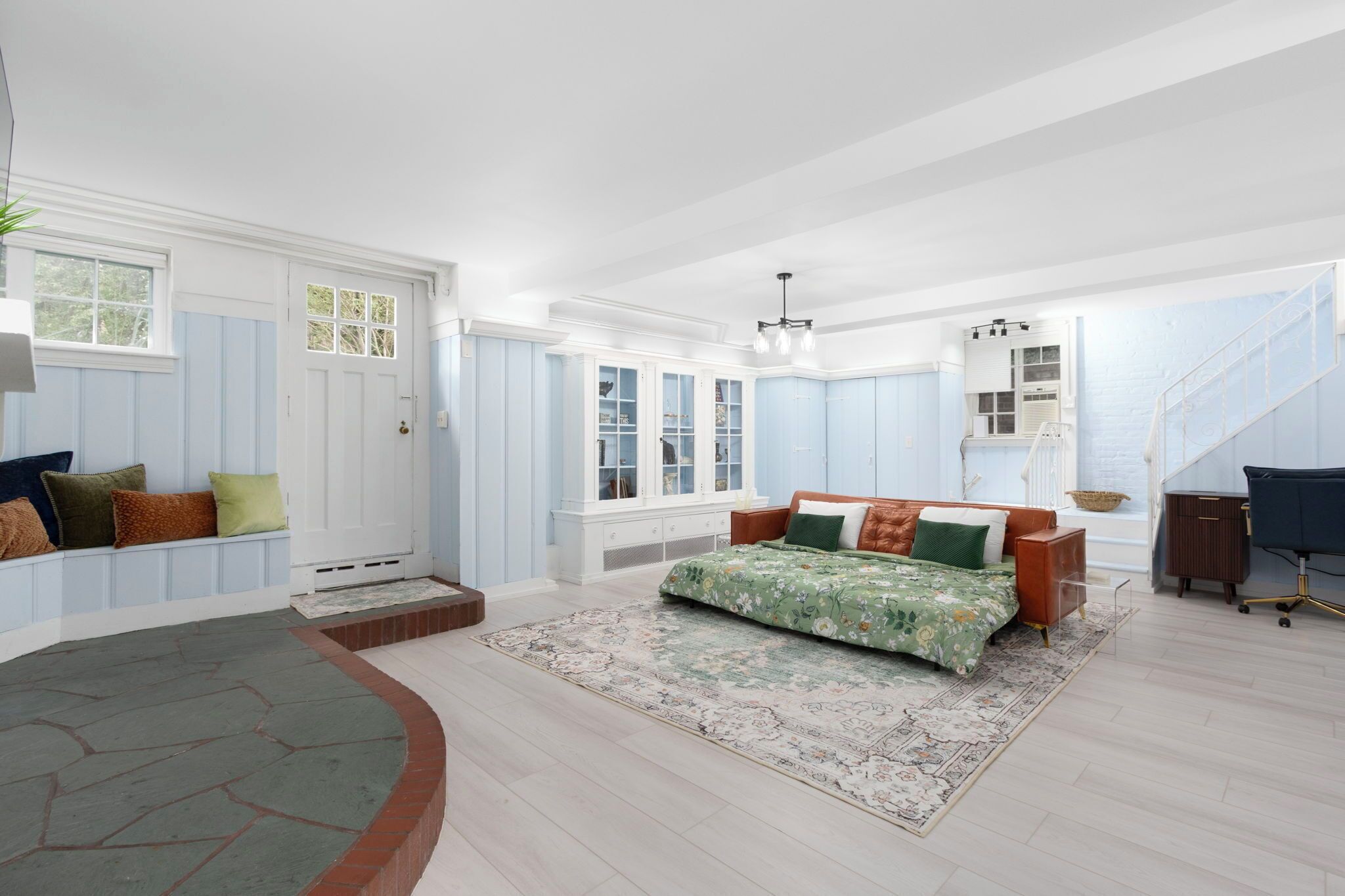 A spacious bedroom with a large bed, a built-in wardrobe, and a staircase leading to an upper level.