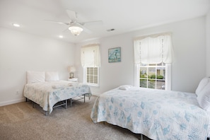 A bedroom with two beds, a ceiling fan, and a window with curtains. - Marina1: walk to marina, restaurants & more on ICW! (Southport)