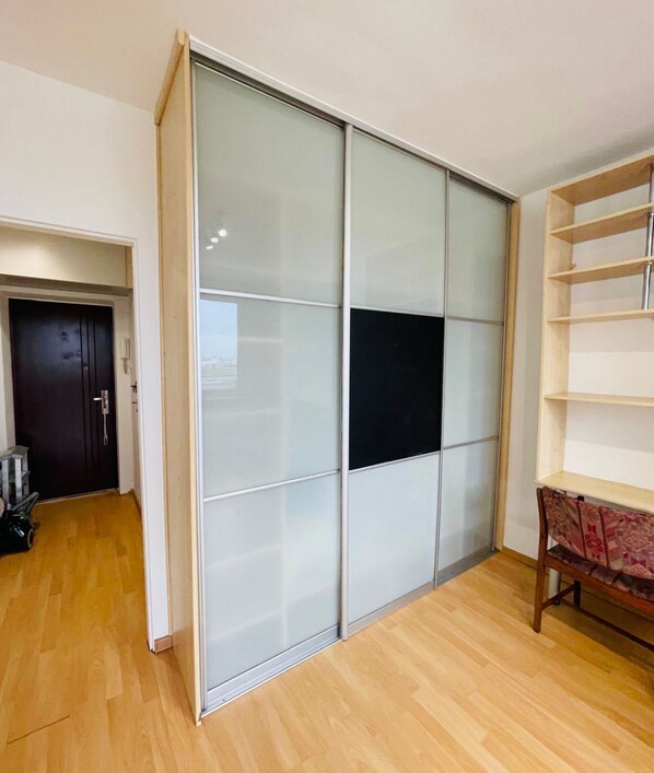 A room with a sliding glass door closet, a wooden floor, and a built-in shelf unit.