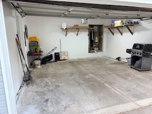 A garage with a concrete floor, a lawnmower, a broom, and a grill. - Charming 3-bedroom townhome with AC in Coeur D’Alene (Coeur D’Alene)