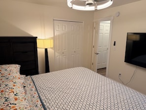 A bedroom with a bed, a dresser, a lamp, a TV, and a door. - Charming 3-bedroom townhome with AC in Coeur D’Alene (Coeur D’Alene)