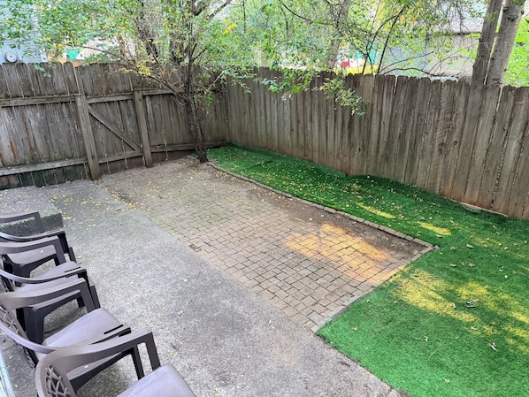 A backyard with a wooden fence, a paved area, and a small patch of artificial grass. - Charming 3-bedroom townhome with AC in Coeur D’Alene (Coeur D’Alene)