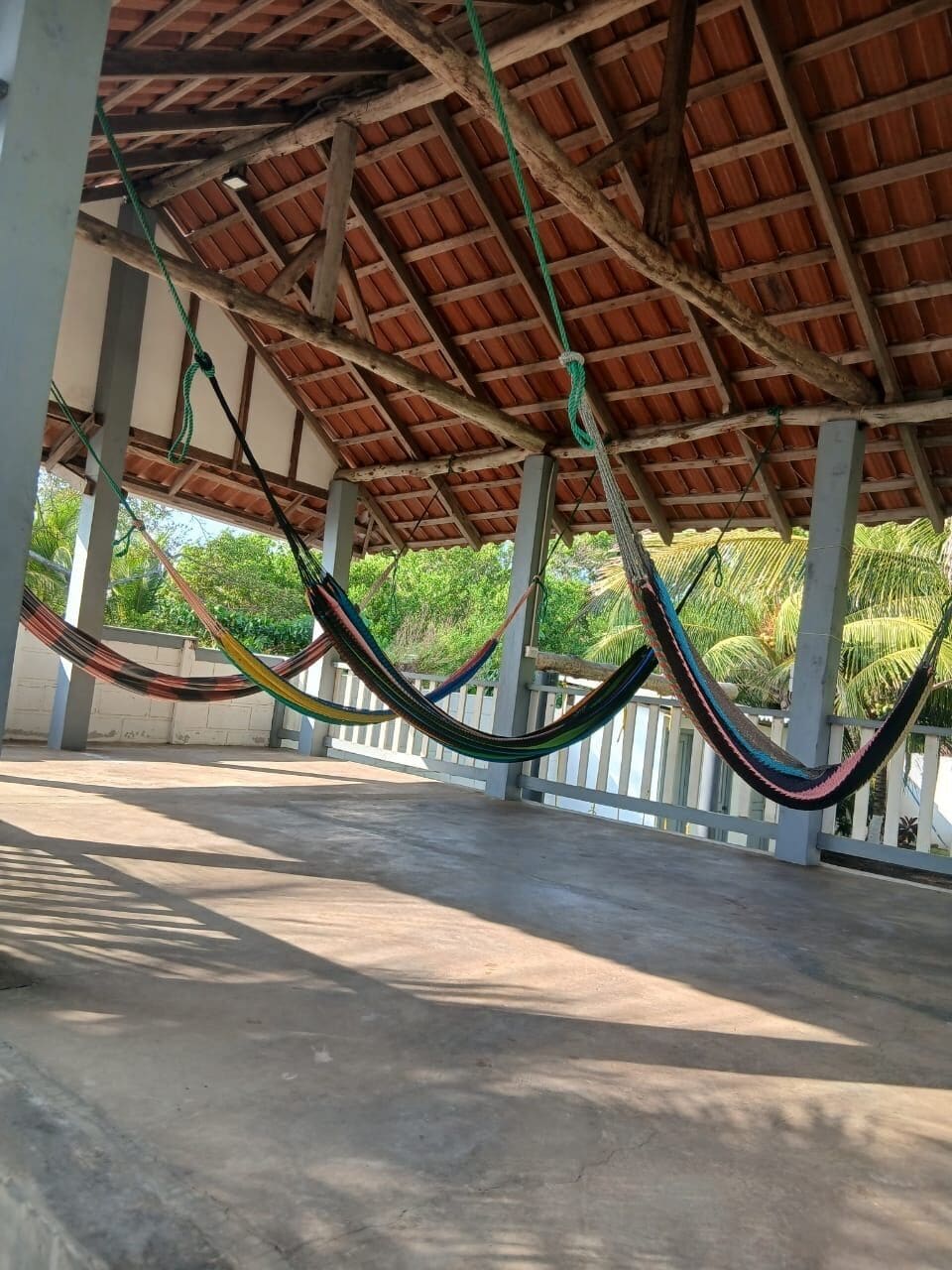 A covered outdoor area with a concrete floor and a wooden ceiling structure.