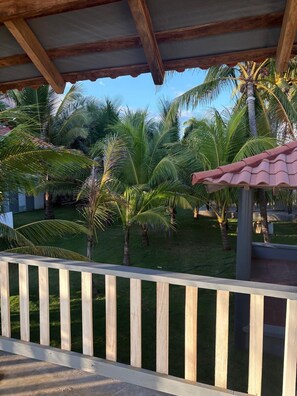 A wooden deck with a view of a well-maintained lawn and palm trees.