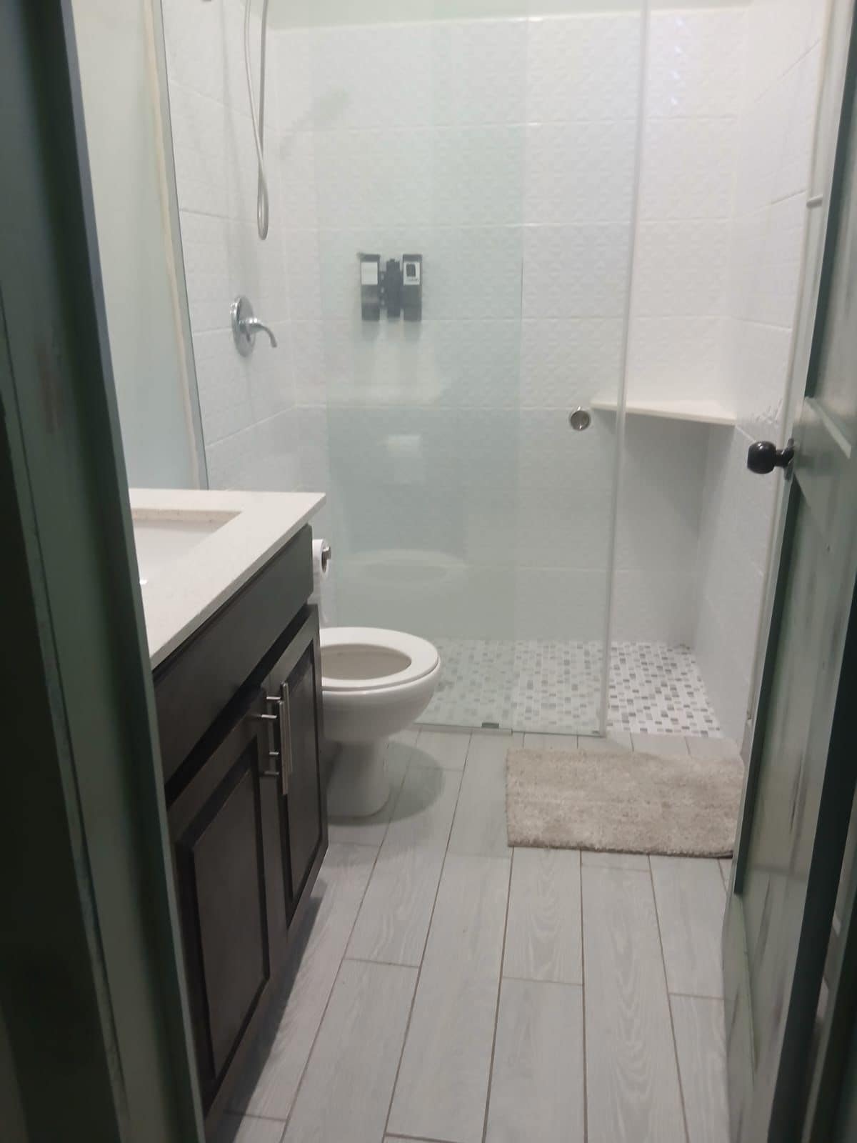 Une salle de bain comprenant des toilettes, un espace douche et un meuble-lavabo avec un miroir.