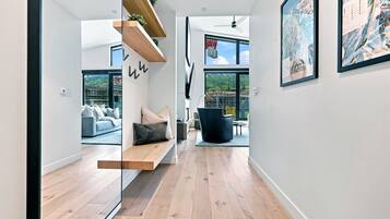 A modern interior with a wooden floor, a bench, a sofa, and a dining area.