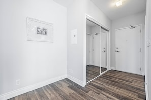 A hallway with a wooden floor, a white door, and a mirror on the wall. - Million Dollars View-Toronto Core two bedroom apartment with balcony and parking (Toronto)