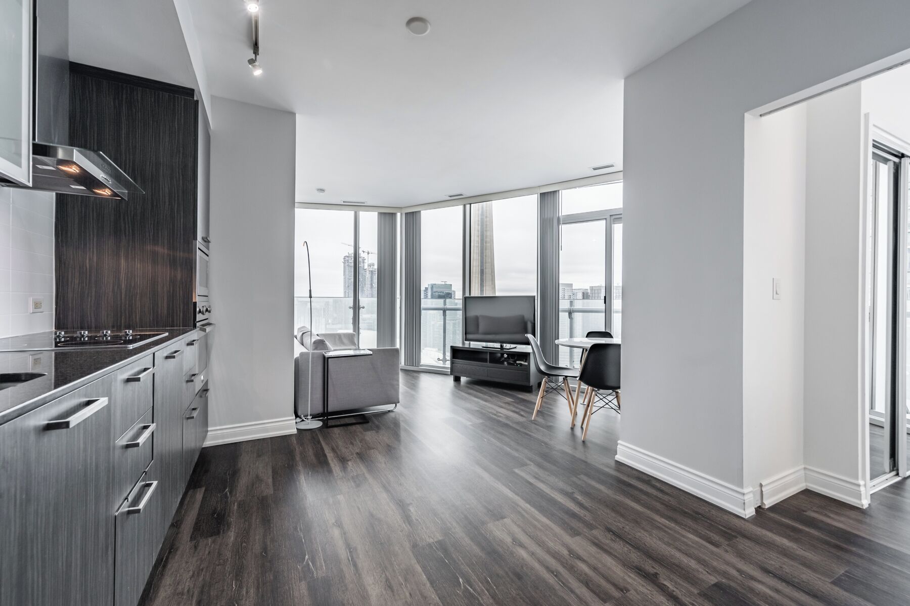 Un appartement moderne doté d’une cuisine, d’un espace de vie et de grandes fenêtres offrant une vue sur la ville.