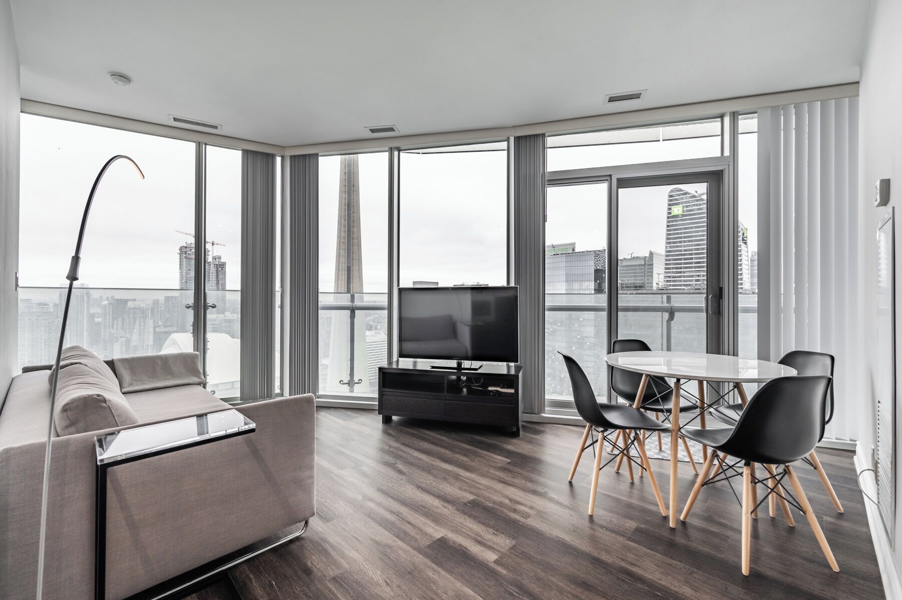 A modern living room with a sofa, a TV, and a dining area with chairs and a table.