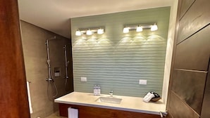 Un baño con tocador de madera, un espejo grande y una zona de ducha.