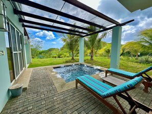 Un área de piscina con dos sillones reclinables, un jacuzzi pequeño y vistas a un jardín exuberante.