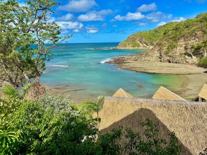 Un paisaje costero con aguas turquesas cristalinas, una playa rocosa y vegetación exuberante.