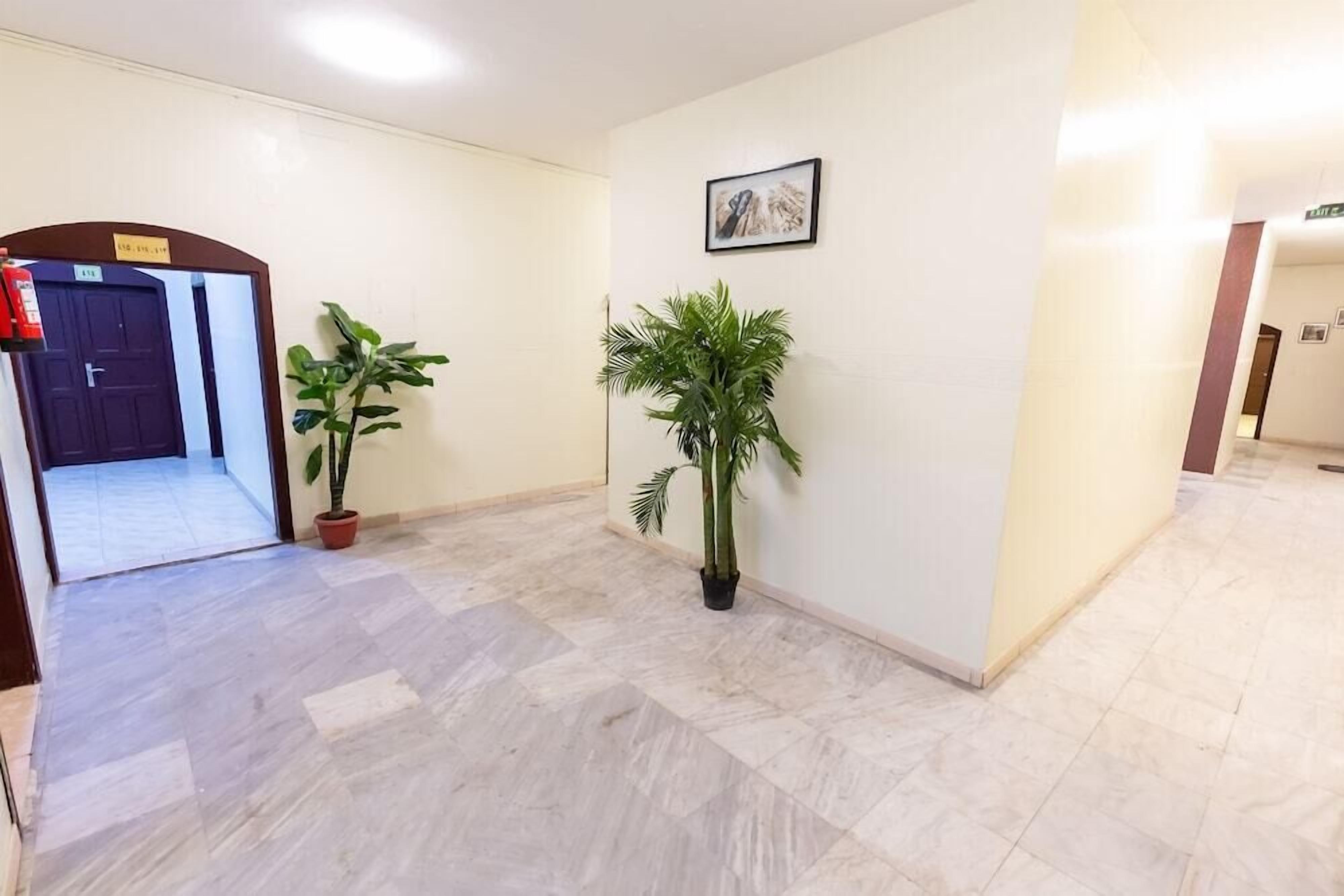 A hallway with a tiled floor, a potted plant, and a framed picture on the wall.