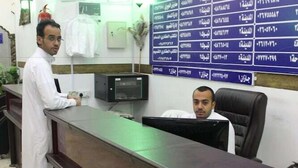 Un mostrador de recepción con un monitor de computadora y un directorio fijado a la pared.