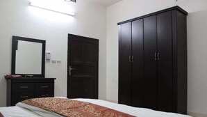 Un dormitorio con cama, armario, espejo y lámpara de pared.