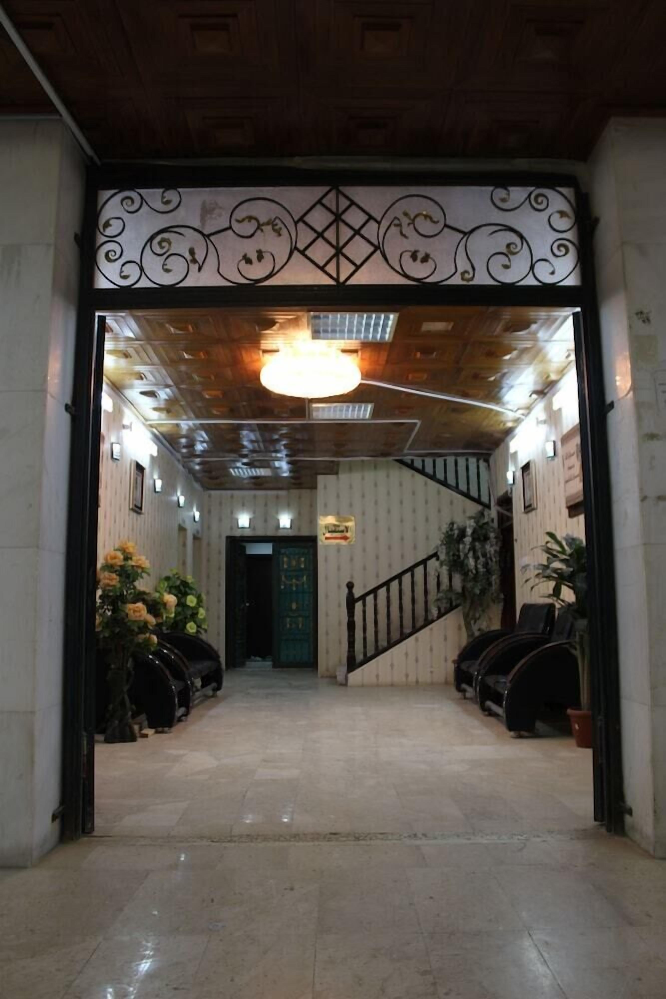 A hotel lobby with a wooden ceiling, a staircase, and potted plants.