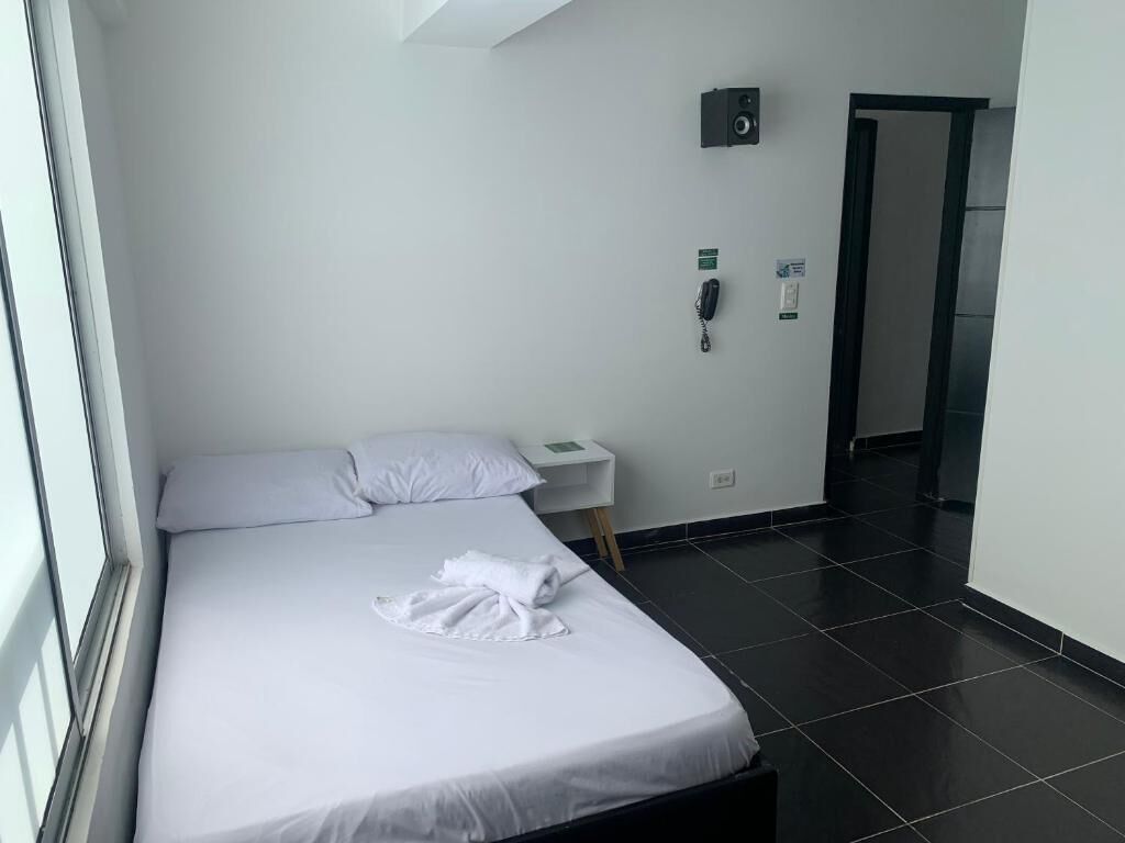 Una habitación de hotel con una cama, una mesita de noche, un teléfono y una puerta.