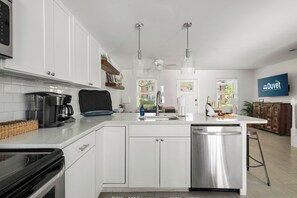 A modern kitchen with white cabinetry, a built-in dishwasher, and a coffee machine. - Lowcountry Retreat | Minutes to Everything! (Mt Pleasant)