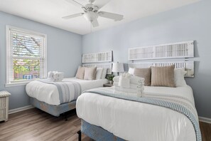 Ein Schlafzimmer mit zwei Betten, einem Deckenventilator und einem Fenster mit Jalousien.