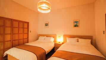 A hotel room with two beds, a wooden wardrobe, and a hanging light fixture.