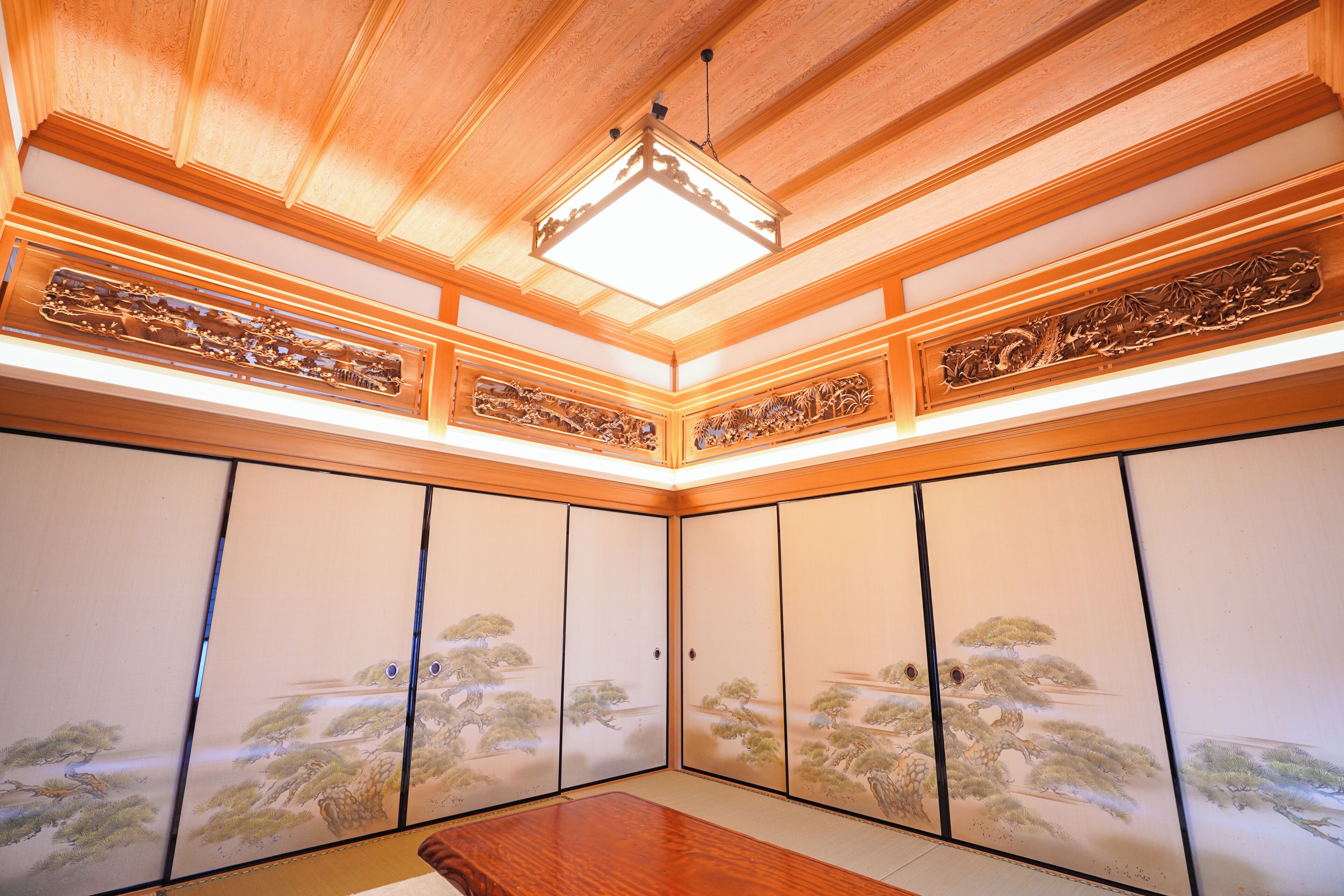 A traditional Japanese room with sliding doors, a wooden ceiling, and a central table.