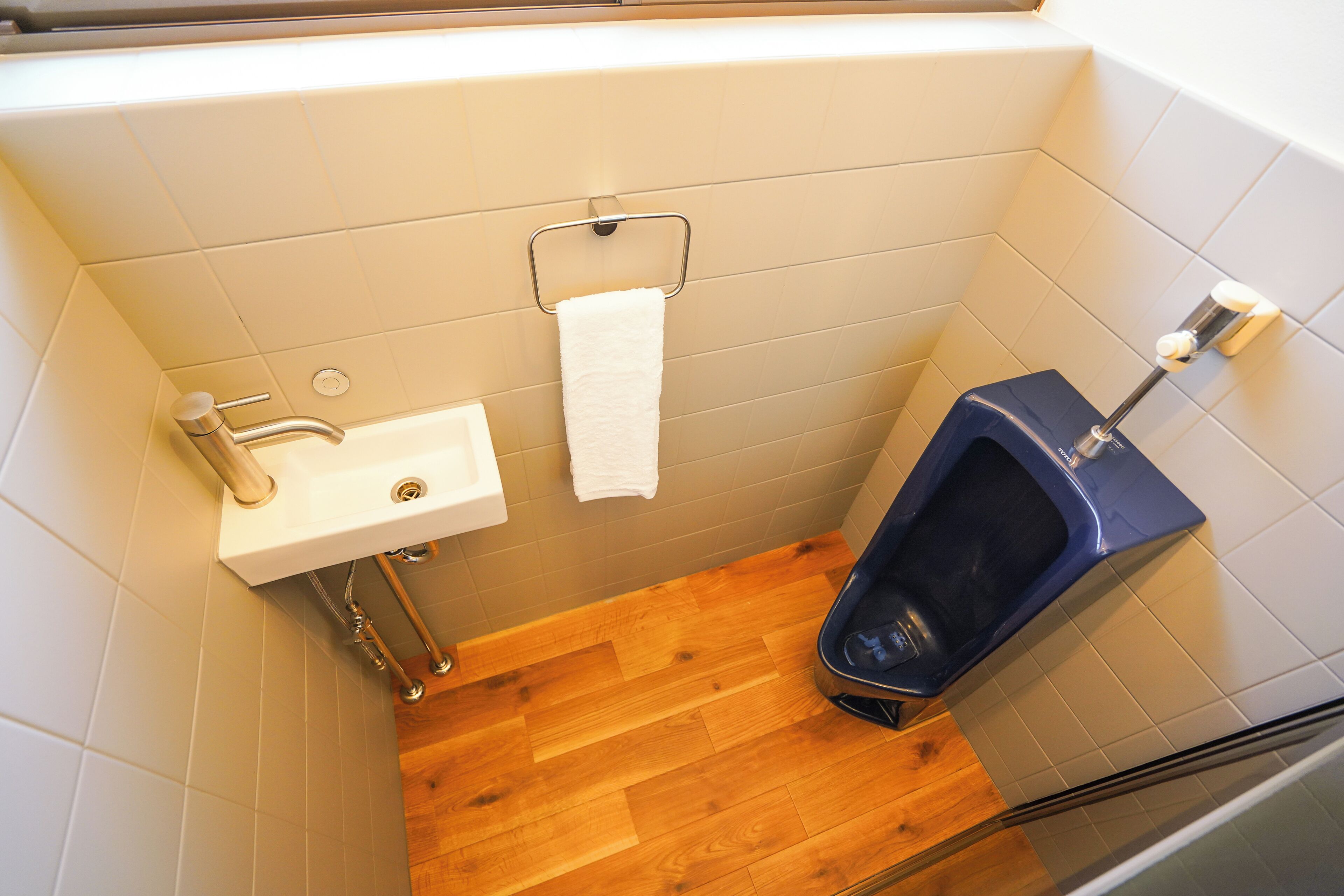 A small bathroom with a sink, a toilet, and a wooden floor.