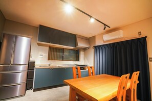 A compact kitchen with a refrigerator, stove, and a window with blinds.