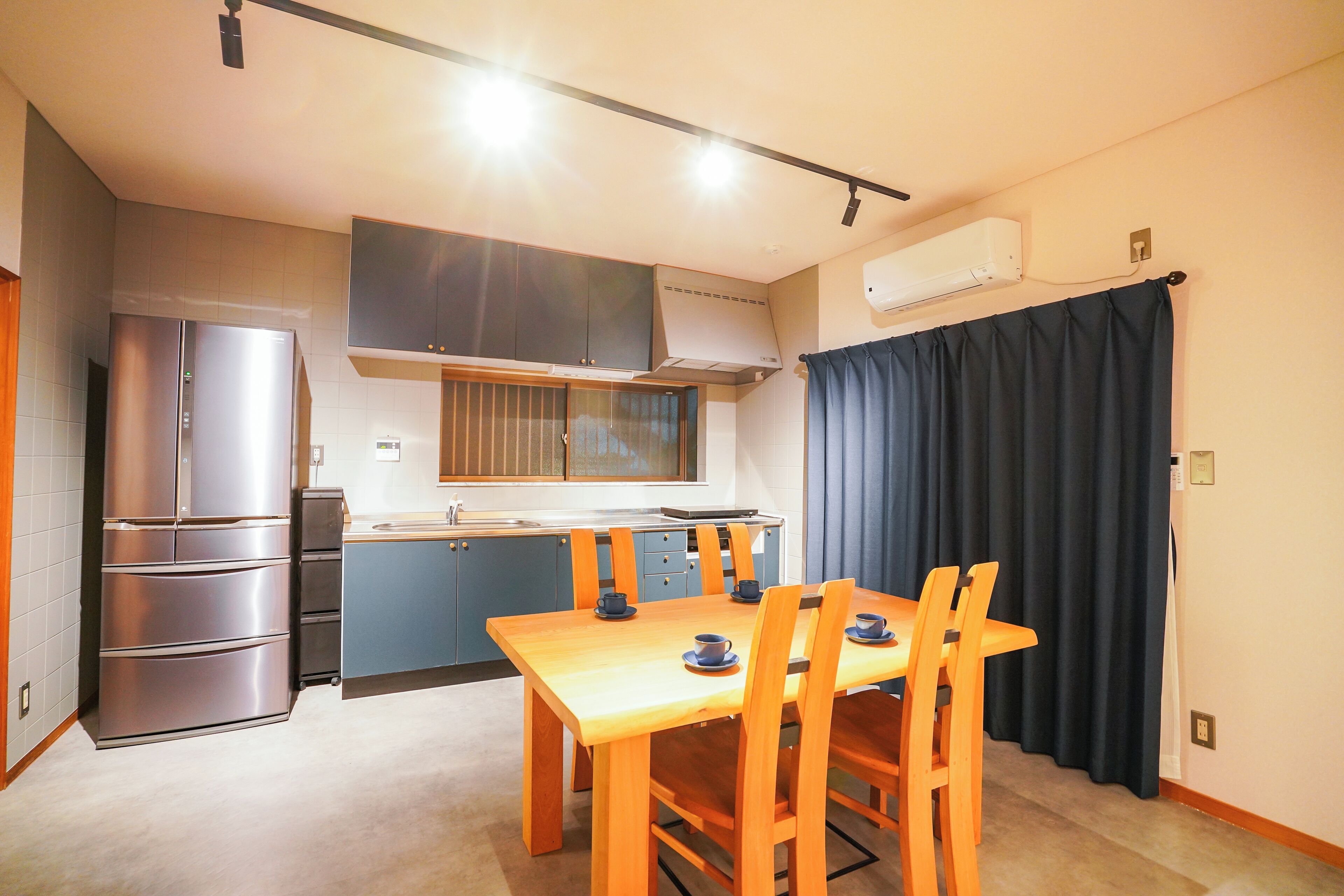 A compact kitchen with a dining area, featuring a refrigerator, stove, and a table with chairs.