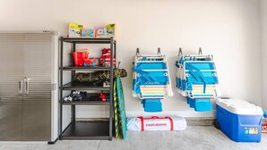 A garage with a storage unit, life jackets, and a cooler. - Low Rates WindMark| Golf Cart + Game Garage Retreat (Port St. Joe)