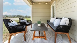 An outdoor patio with a table and two sofas, a potted plant, and a view of a grassy area. - Low Rates WindMark| Golf Cart + Game Garage Retreat (Port St. Joe)