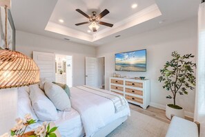 A bedroom with a bed, a ceiling fan, a dresser, a television, and a plant. - Low Rates WindMark| Golf Cart + Game Garage Retreat (Port St. Joe)
