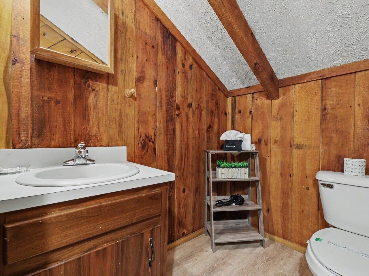 A bathroom with wooden walls, a white sink, and a toilet.