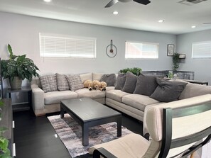 A modern living room with a sectional sofa, a coffee table, and a dining area with a small table and chairs. - Family-Friendly Getaway for Disneyland Vacation with 2 bedrooms and  2 baths (Santa Ana)