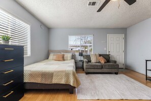 A bedroom with a bed, a dresser, a gray sofa, and a window with blinds. - Private Studio Guesthouse with Everything! (Los Angeles)