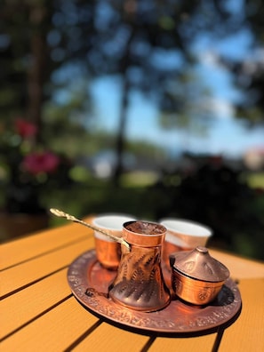 A copper tea set on a wooden table outdoors.