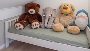 Ein weißes Babybett mit Matratze, an einer weißen Wand platziert.