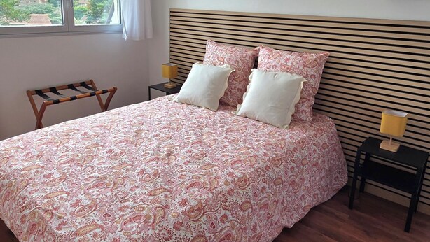 Una camera da letto con un letto grande, due comodini, una sedia e una finestra con tende.