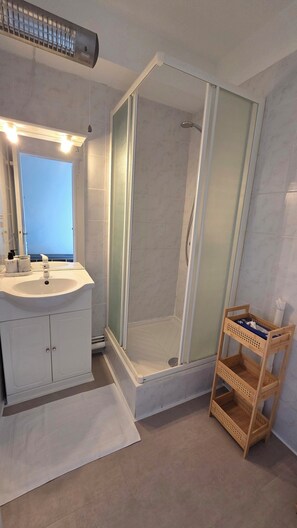 A bathroom with a shower, a sink, and a vanity. - Appartement rénové et lumineux à 50 mètres de la mer et de la promenade. (Cabourg)