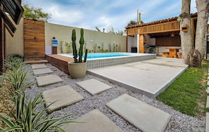 Une piscine dotée d’une terrasse carrelée, entourée d’une zone de gravier et de dalles permettant de traverser.