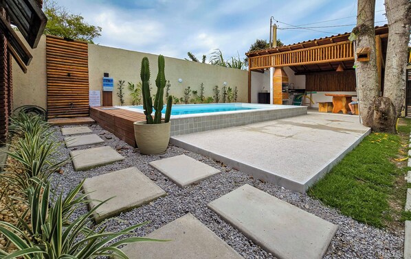 A swimming pool with a tiled deck, surrounded by a gravel area and stepping stones.