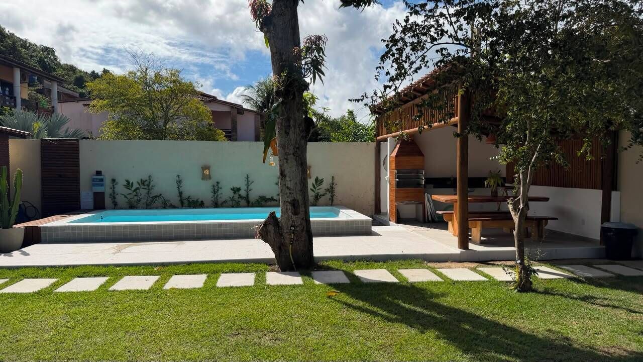 Ein Garten mit Swimmingpool, einer Holz-Pergola und einem Grillplatz.