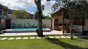 A backyard with a swimming pool, a wooden pergola, and a barbecue area. - CASARÃO SOL DA MANGUEIRA: High standard, 150m from the beach, 5 suites, swimming pool and leisure area. (Santa Cruz Cabrália)