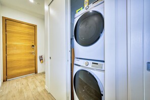 A laundry room with two stacked washing machines and a wooden door. - Lush Oasis in the heart of 7mile Beach Area (George Town)