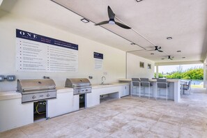 Ein Außenpoolbereich mit Grillstation, Sitzgelegenheiten und einem Schild, das Poolregeln erklärt.