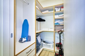 A closet with shelves, a hanging rack, and a vacuum cleaner. - Lush Oasis in the heart of 7mile Beach Area (George Town)