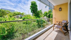 Ein Balkon mit Glasgeländer, einem Stuhl und einem Tisch.