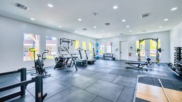 Une salle de sport équipée de divers appareils d’exercice, dotée de grandes fenêtres et présentant un design moderne et épuré.